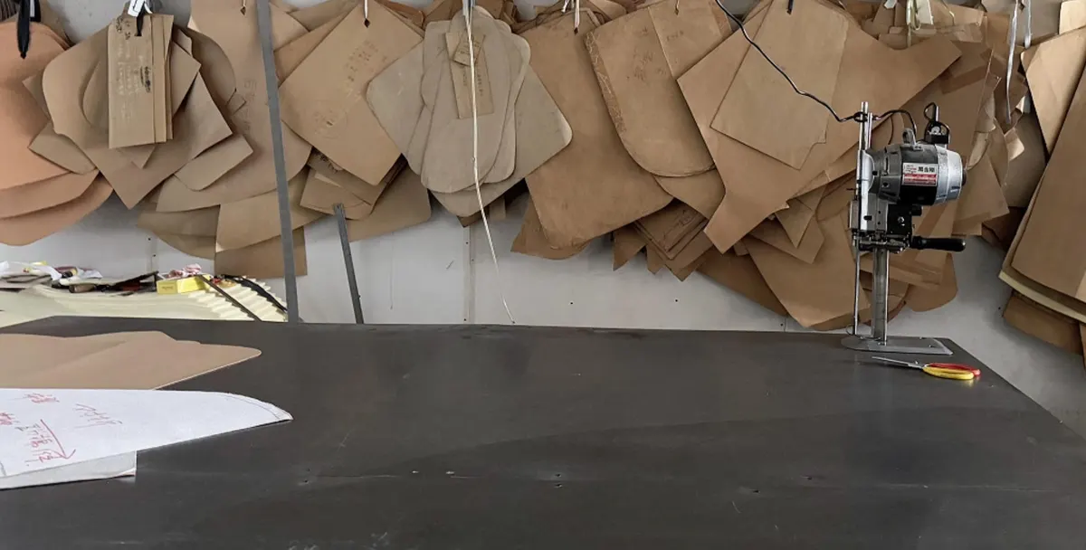 Upholstery paper patterns hanging above a cutting table with an electric fabric cutter
